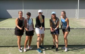 5 kvinnor med tennisrack på en tennisbanan